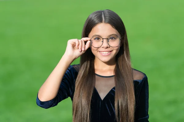 Het gezicht dat je verdient. Klein kind kijkt door glazen groen gras. Pediatrische oogheelkunde. Zichtcorrectie. Optische eyecare. Een schoonheid van een klein meisje. Kapsalon — Stockfoto