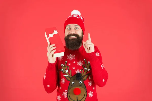 Homem barbudo feliz vestindo camisola de malha engraçada e chapéu de santa claus e segure a caixa presente tem uma ideia para celebrar a festa de ano novo, compras de ano novo — Fotografia de Stock
