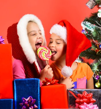 Noel Baba şapkalı kız kardeşler yılbaşı ağacının yanında otururlar..