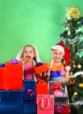 Noel Baba şapkalı kız kardeşler hediye kutularının arkasında duruyorlar..