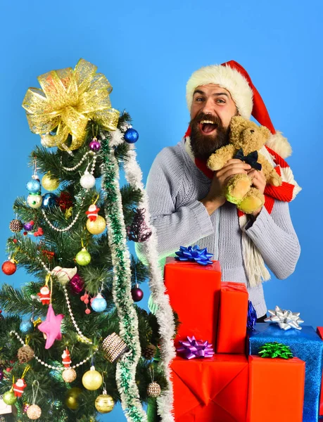 Guy in red hat with xmas gift boxes and bear