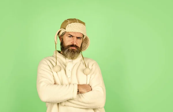 Kapper diensten. Een man met een baard draagt een hoed met oorkleppen. Harige accessoire. Wintermode. Koud weer. Het winterseizoen voor baardverzorging. Gezichtshaar concept. Pelskleding. Een bebaarde hipster. Kapsalon — Stockfoto