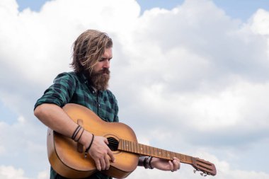 Sakallı ve bıyıklı adam gitar çalıyor. Kareli gömlekli sakallı adam şarkı söylüyor. Müzisyen müzisyen. müzik teli enstrümanı. Olgun karizmatik erkek gitarist