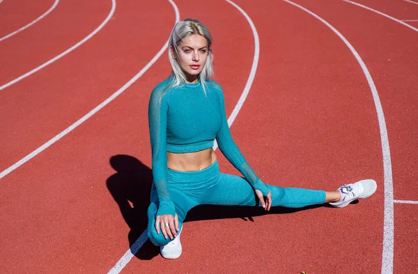 Seksuele atletische vrouw in fitness kostuum stretching op hardlopen track, sport — Stockfoto