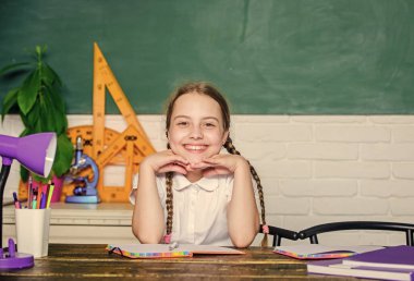 Öğrenmeye bağlı. Küçük çocuk okulu. Bilgi toplama günü. Geleceğe doğru hızlanıyor. Hometask konsepti. Eylülün birinde okula dönüyorum. Şirin kız okuldaki karatahta sınıfında oturuyor.