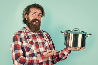 Ürün sunumu. Adam yeni marka tavayı tutuyor. Mutfak gereçleri. Mutfakta erkeklerin ellerinde demlik pişiriyorum. Yemek hazırlamak ve yemek pişirmek. Mutfak aletleri. Mutfak reklamı. Tencereli adam.