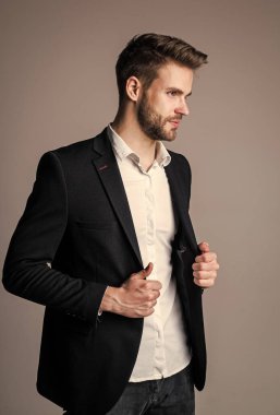 Genç ve özgür. Gömlek ve ceket giyen kendine güvenen bir iş adamı. patron erkek. Gri arka planda seksi CEO. Modern ofis hayatı. Karizmatik iş sahibi. Şık bir emlakçı. Yakışıklı adam resmi takım elbise giyiyor.