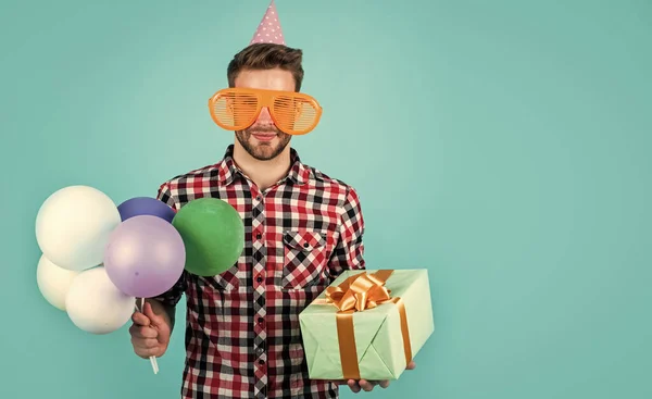 Handlar i köpcentret. Rolig man i födelsedagshatt. Killen håller festliga ballonger. Glad högtid firande. Dags för skoj och presenter. Grattis på födelsedagen eller årsdagen. Känn glädje och glädje. ren sällskapsgås — Stockfoto