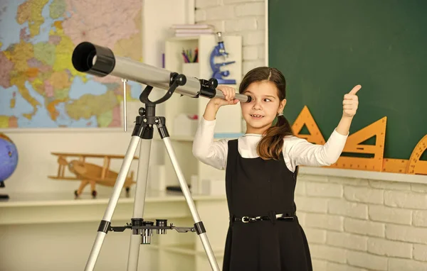 Lärardagen. En liten flicka som använder teleskop. Teleskop på stativ. Skolämnen inställda. Skolastronomi lektion. Utforska rymden och planeterna i nya galaxer. Skolflicka tittar igenom teleskopet — Stockfoto