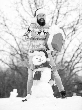 Sürpriz konsept. Kış oyunları. Kış aktivitesi. Kış tatili Adam kardan adam yaptı. Noel Baba şapkalı adam dışarıda eğleniyor. Adam gülen surat, karlı doğa geçmişi. Sakallı hippi. Hediye kutusu.