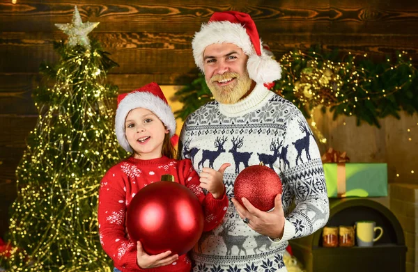 Baba ve kızı Noel 'i kutluyor. Xmas partisi. Aile evi ve Noel ağacını süsler. Kış Xmas tatili. Mutlu yıllar. Sakallı baba ve küçük kız Noel Baba şapkası. Komik örgü süveter. — Stok fotoğraf