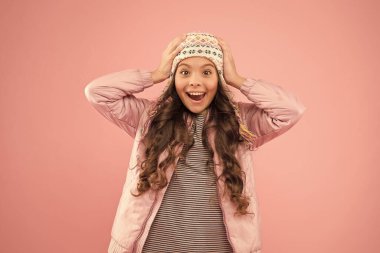 Mutluluk dolu. Soğuk mevsim için sıcak kıyafetler. Örülmüş aksesuar. Küçük kız kış şapkası. Çocuk modası. Moda kızı hipster 'a benziyor. Şaşırmış çocuk pembe arka planı. Sonbahar tarzı. Mutlu çocukluk