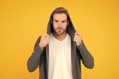 Rahat hissediyorum. Genç adam tarzı sarı arka plan. Sıradan tarzda yakışıklı bir adam. Genç manken kapüşonlu giyiyor. Genç erkekler için moda trendleri. Genç ve çağdaş