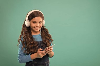 Küçük kız mp3 çalar tutuyor. En sevdiğin şarkıyı seç. Modern hayatta e-öğrenim. Liseli kız yeni teknoloji kullanıyor. kopyalama alanı. Çocuk kulaklıkla müzik dinliyor. Küçük çocuk akıllı telefondan çalma listesi yapıyor