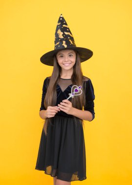 Mutlu çocuk cadı şapkası takar sihirli değnek tutar Cadılar bayramında büyü yaratmak için, mutlu cadılar bayramı