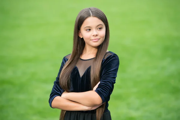 Mi sento sicuro di me. Ragazza fiduciosa tenere le braccia incrociate erba verde. Look di bellezza della piccola fashionista. Salone da parrucchiere. Stile trendy. Moda tendenza. Outfit che aumenterà la vostra fiducia — Foto Stock