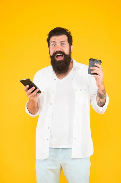 Oh, Dios mío. hombre barbudo maduro charlando por teléfono mientras bebe café. bebida de la mañana en taza de papel. la vida moderna. sorprendido chico con bigote y barba beber café celebración smartphone —  Fotos de Stock