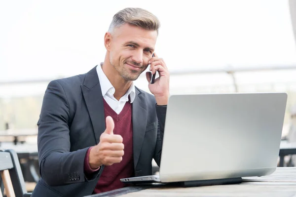 Glücklicher Geschäftsmann zeigt Daumen nach oben Handgeste im Gespräch mit dem Kunden auf dem Handy und mit dem Computer für Geschäfte online, Genehmigung — Stockfoto