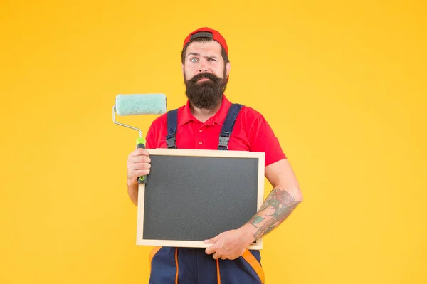 Серйозний бородатий чоловік художник у костюмі котла, використовуючи інструмент для малювання стіни і тримаючи крейду для копіювання простору, викладання і вивчення реконструкції — стокове фото