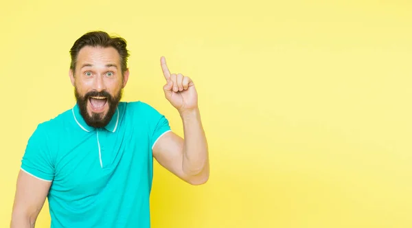 Vilken bra idé. Stilig leende mogen man hålla fingret upp och titta på kameran när du står mot gul bakgrund. Människan skäggigt glad ny idé. Idéernas födelse — Stockfoto