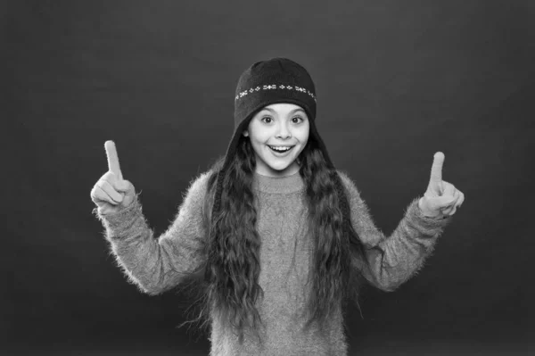 Ide nézz! Kislány téli divat kiegészítő. A kisgyerek kalapot visel burgundi háttérrel. Aranyos modell élvezni téli stílusban. Bemutató koncepció. Téli ruha. A kisgyerek kötött sapkát visel. Maradj meleg. — Stock Fotó