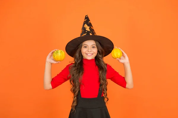 Bambino felice con i capelli lunghi indossare cappello strega tenere zucca per jack o lanterna a festa di autunno, felice Halloween — Foto Stock