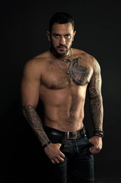 Sport and fitness. Masculinity. Muscular torso. Jewelry for real men. Bearded man with tattooed torso. Macho sexy bare torso. Fit model with tattoo art skin. Sportsman or athlete with beard and hair