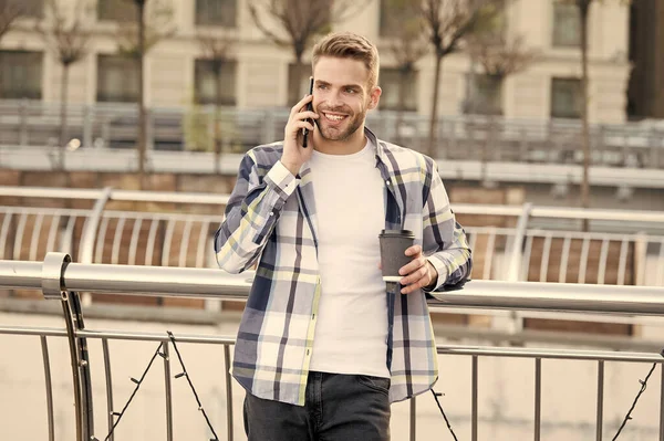 Conversación con un amigo. Llámame más tarde. Reunámonos en unos minutos. Comunicación de la vida moderna. Tipo moderno con fondo urbano smartphone. Hombre guapo teléfono móvil y taza de café. Tecnología moderna — Foto de Stock