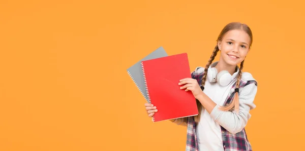 Torniamo a scuola. utilizzare notebook o libro. Lezioni di studio per esame. trovare ispirazione nel libro. Mi piace lo studio. Fiduciosa nella sua conoscenza. bambino piccolo in cuffia con blocco note. bambino pronto a studiare — Foto Stock