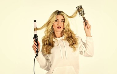 Farklı ambalaj teknikleri kullanarak. İhtiyaçlarınız için doğru saç maşasını seçin. Sevimli sarışın kız. Çevrimiçi iş. Saç stili oluşturun. Uzun kıvırcık saçlı kadın saç maşası kullanıyor. Kuaför ipuçları