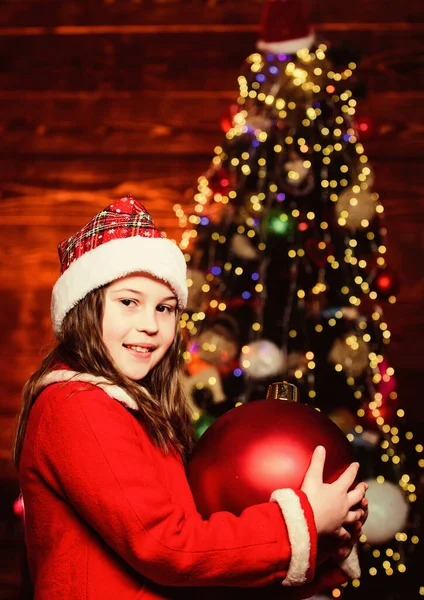 Parlak büyük bir oyuncak. Şenlikli atmosfer noel günü. Kız Noel Baba kostümü büyük noel ağacı süsleri içerir. Noel süsleri. Etraftaki her şeyi dekore etmeye bayılırım. Mutlu Noeller. — Stok fotoğraf