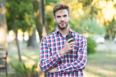 Elinde kahve ile birlikte kağıt bardak tutan yakışıklı bir adam. Sabah kahvesi içen adam. Her havada sıcak çay. Günaydın içecekler. Kendine güvenen iş adamı