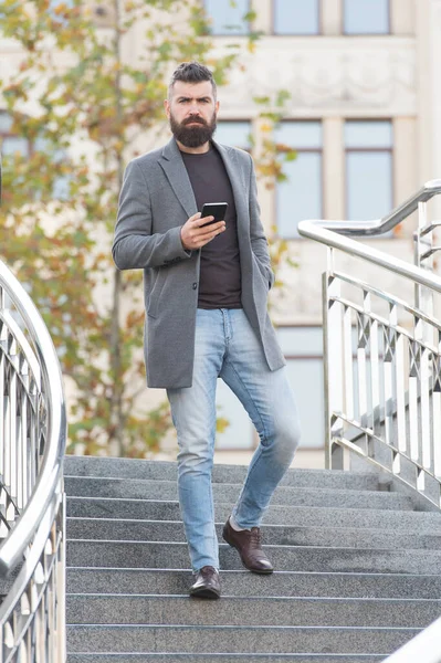 Rušný hipster v příležitostném obchodním stylu jít dolů po schodech držící mobilní telefon městský venku, muž — Stock fotografie