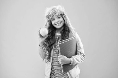 Kış dönemi. Sırt çantası ve kitapları olan bir genç. Sağlıklı atıştırmalıklar. Modern eğitim. Şık bir kız öğrenci. Küçük gülümseyen liseli kız elma meyvesi tutuyor. Öğrenci kız günlük yaşamında mutlu. Noel tatili