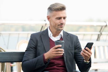 Aramanız önemli. İş adamı elinde kahve fincanıyla cep telefonuna cevap veriyor. Kahve molası. Sıcak içecek. Gün içinde dinlenme molası. Modern teknoloji. İş iletişimi