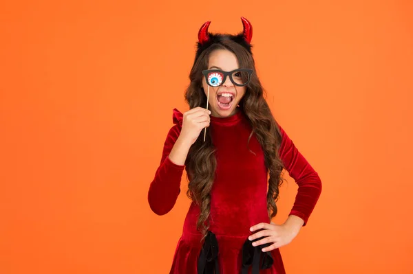 Lustiges Kind im Hexenkostüm zu Halloween mit Partybrille und Teufelshörnern auf orangefarbenem Hintergrund, Halloween-Horror — Stockfoto