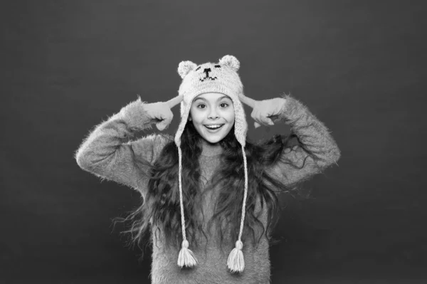 Traje de invierno. Un niño pequeño usa un sombrero de punto. Mantente caliente. Pequeña niña accesorio de moda de invierno. Niño pequeño pelo largo usar sombrero fondo rojo. Lindo modelo disfrutar del estilo de invierno. Osito de peluche. Siendo lindo oso — Foto de Stock