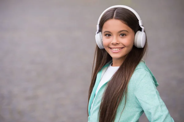 Chica de la escuela feliz escuchar música o audio libro en auriculares para la educación y la alegría, nueva tecnología, espacio para copiar —  Fotos de Stock