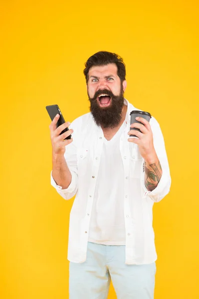 Skrik killen med skägg och mustasch har mobiltelefon. morgonrutin. använda modern teknik. arg skäggig man som håller telefonen medan han dricker kaffe. Brutalt hipsterdrickande dryck — Stockfoto