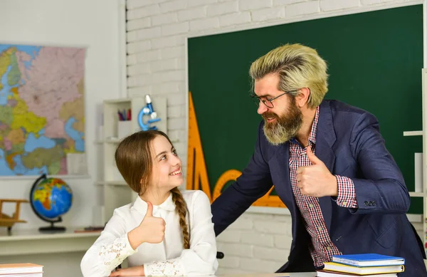 Klein meisje en man tegen schoolbord. Kennisdag. Kind met leraar in de klas. Lerarendagconcept. Adviserende student. Thuisschoolproject. Schoolmeisje studeren met persoonlijke tutor — Stockfoto