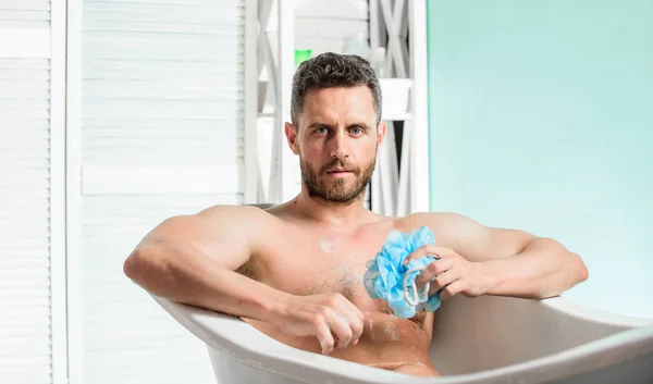 Sex and relaxation concept. Wash off foam with water carefully. Macho naked in bathtub. Macho attractive nude guy. Sexy man in bathroom. man wash muscular body with foam sponge. stop contamination