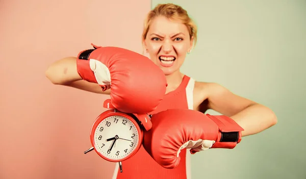 Sportswoman. win the day. angry woman boxing gloves. girl boxer hold alarm clock. morning energy. full of power. activity time. Establishing the clock time. time to fight. time for success