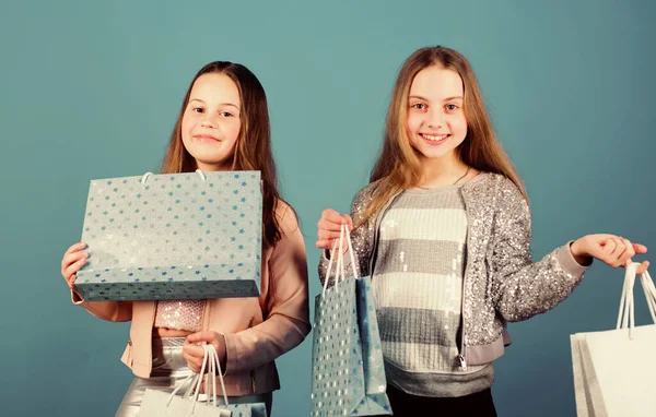 姉妹と家族。購入の節約です。販売と割引。子供のファッション。青の背景。ショッピングバッグを持つ小さな女の子。幸せな子供たち。妹たちよ。姉妹の概念。家族の日 — ストック写真