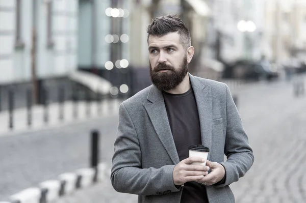 Businessman well groomed enjoy coffee break outdoors urban background. Thoughtful but relaxed. Walk and enjoy fresh hot coffee. Involved in relaxation. Man bearded hipster drink coffee paper cup — Stock Photo, Image