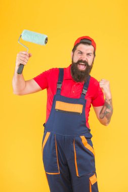 Boilersuit üniformalı mutlu vahşi adam. Olgun hippi resim yapmak için boya silindiri kullanıyor. Tamirci ya da inşaatçı çalışıyor. yaratıcı fikir. Ustabaşı duvara bakacak. keşif araçları