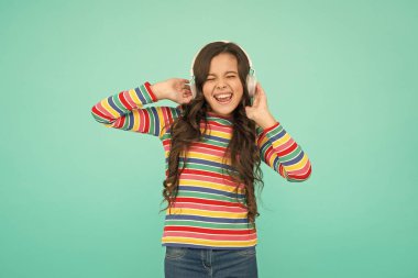 Dalgamı yakala. Küçük kız kulaklıkla müzik dinliyor. Çocuklar için sesli kitap edebiyatı. Genç çocuk pozitifliğini ifade ediyor. İyimser liseli kız renkli kıyafetler giyiyor. En iyi yaz vuruşları. pozitif tonda