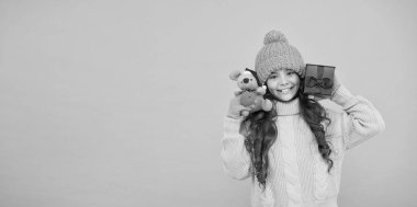 Alışveriş ipuçları. Yılın fare sembolü. Mutlu kız fare oyuncağı ve paketlenmiş hediye kutusu tutuyor. Çocuk süveter ve şapka örüp pelüş oyuncak oynuyor. Çocuklar için alışveriş. Mutlu 2020 yılları. İyi şans için bir hediye. Hediyeyle eğlen.