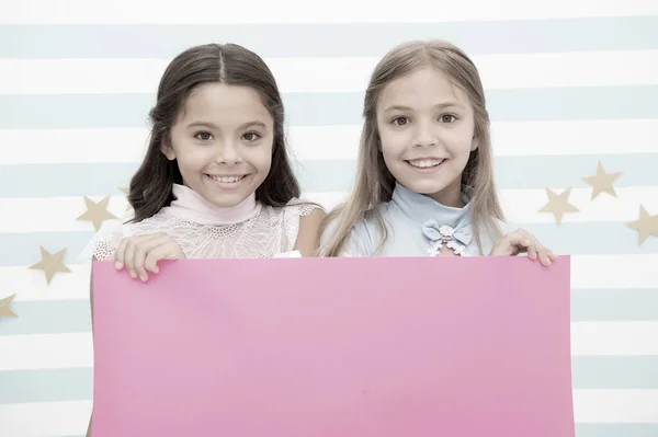 아이들을 위한 학교 발표. 당신의 광고여기. 학교 발표를 위해 분홍색 종이를 들고 있는 어린 소녀들. 복사 공간을 위한 분홍색 배경. — 스톡 사진