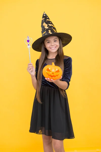 Счастливая девушка носить колпак ведьмы держа волшебную палочку и тыквенный валет о фонарь, чтобы создать чары на Хэллоуин, Хэллоуин колдовство — стоковое фото