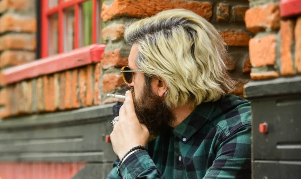 Hipster smoking old architecture background. Medical cannabis. Guy in sunglasses smoking tobacco. Smoking outdoors. Smoking habit. Man with cigarette. Cool guy relaxing. Reduce stress. Mental health